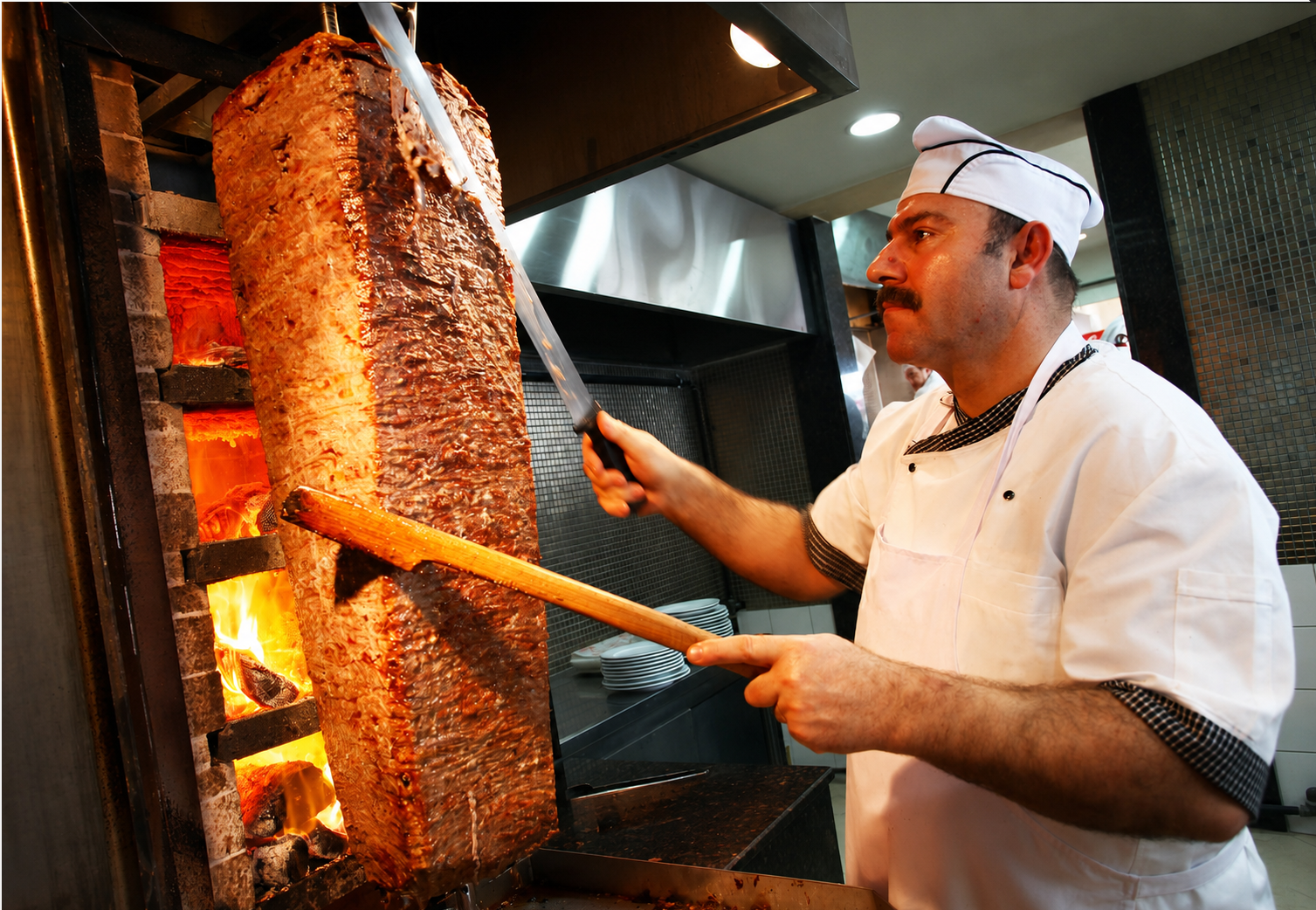 Chef slicing fresh halal döner from the vertical rotisserie at Capital Pizza & Doner Gyro Shawarma in Arlington VA